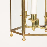 A Colefax and Fowler gilt brass hexagonal hanging lantern with scroll decorated top and finials. Late 20th century. Rewired.