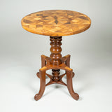An unusual 19th century round table with a rotating parquetry top, turned mahogany support and a four footed base