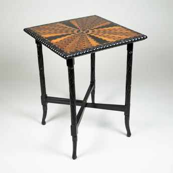 An Anglo Indian ebony table with a specimen inlaid top in a radiating design with a gadrooned edge and with spiral carving to the legs.