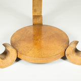 A low round sycamore table, the segmentally veneered top on three scroll supports joined by a lower tier. 20th century. French circa 1940.