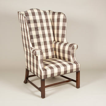 A high-backed Chippendale period wing arm-chair with mahogany moulded legs and cross-stretcher. English, circa 1770.