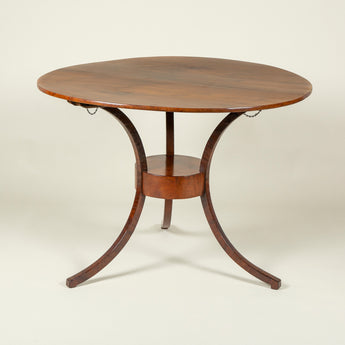 An early 19th century Italian mahogany campaign table, the round top on a three-legged base.