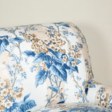 A large three seat sofa in a traditional style upholstered in a floral chintz fabric in blues and browns on a white ground.