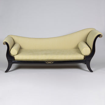 An elegant Regency sleigh-shaped sofa, with a low back and ebonised beech wood frame with sabre legs and brass mounts. Circa 1810.