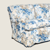 A large three seat sofa in a traditional style upholstered in a floral chintz fabric in blues and browns on a white ground.