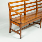 A stylish early 19th century long elmwood settle with a triple ladder back and elegant turned legs.