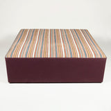 A modern large square ottoman, the top covered in a vintage Persian flat weave rug.